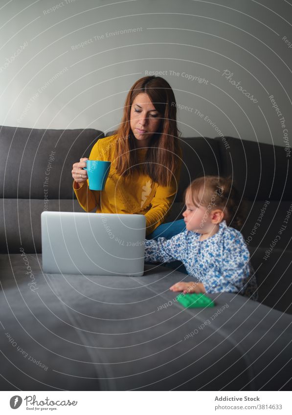 Geschäftsfrau mit kleinem Kind arbeitet am Laptop zu Hause Mutter Arbeit benutzend Kaffee trinken beschäftigt abgelegen online freiberuflich Kleinkind Tochter
