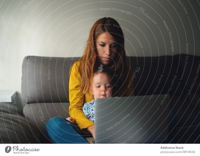 Frau mit kleinem Kind mit Laptop zu Hause Mutter Arbeit benutzend beschäftigt Kleinkind abgelegen wenig Tochter Zusammensein Mutterschaft Apparatur Gerät
