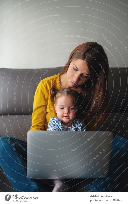 Frau mit kleinem Kind mit Laptop zu Hause Mutter Arbeit benutzend beschäftigt Kleinkind abgelegen wenig Tochter Zusammensein Mutterschaft Apparatur Gerät