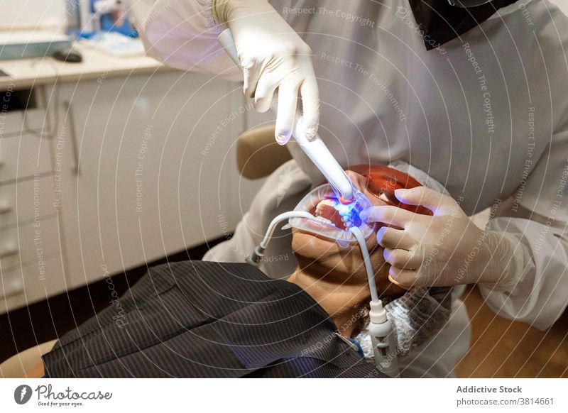 Zahnarzt behandelt Zähne eines Patienten mit UV-Licht ultraviolett Gerät Zahnmedizin Kur Stomatologie Werkzeug dental professionell Klinik Medizin mündlich