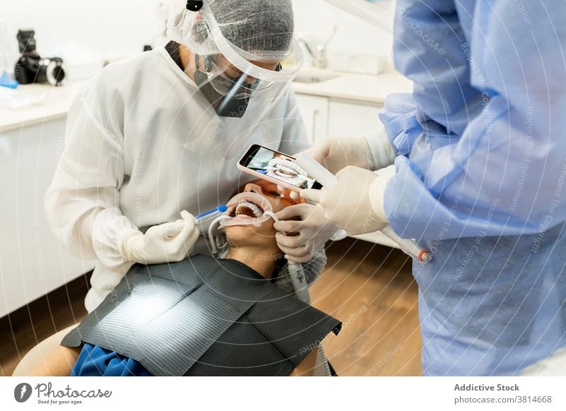 Zahnärzte beim Fotografieren der Zähne eines Patienten Zahnarzt fotografieren Smartphone geduldig Zahnmedizin Stomatologie Gerät dental professionell Klinik