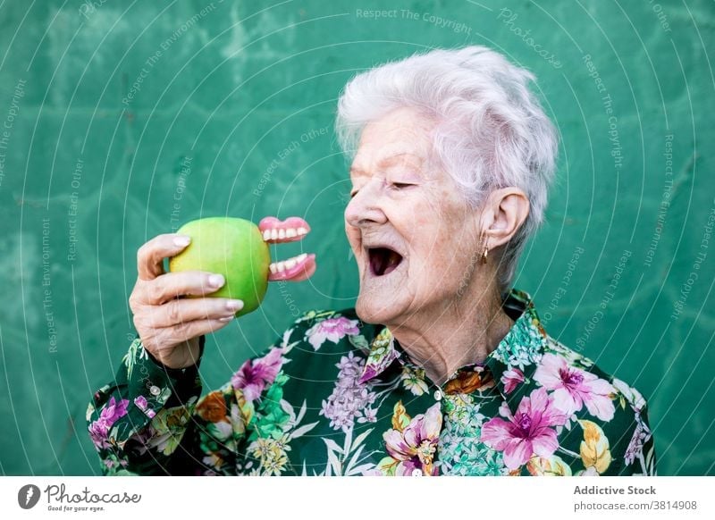 Lustige ältere Frau mit Apfel und Gebiss Senior Zahnersatz Zähne lustig Witz Humor trendy Stil Biss Accessoire Dame alt Gesundheitswesen Mund gealtert