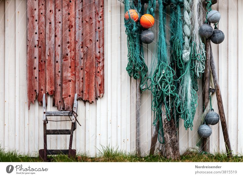 Maritimes Stillleben an einer Hauswand in Norwegen netze fischernetz boje holz brett karre sackkarre leine seil tau tauwerk maritim hafen holzhaus zierrat