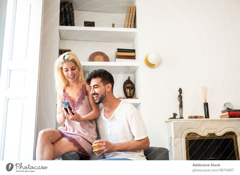 Lächelndes Paar genießt den Morgen zusammen zu Hause Zusammensein früh genießen Pyjama Nachtwäsche Angebot Smartphone Saft Glas Gerät Apparatur Gespräch