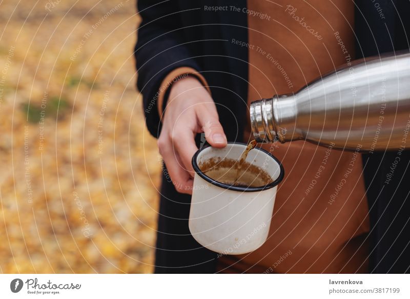 Nahaufnahme von Frauenhänden, die im Freien heißen Tee in eine Emaille-Tasse gießen Becher wandern trinken Lächeln Freizeit Thermoskanne Picknick reisen