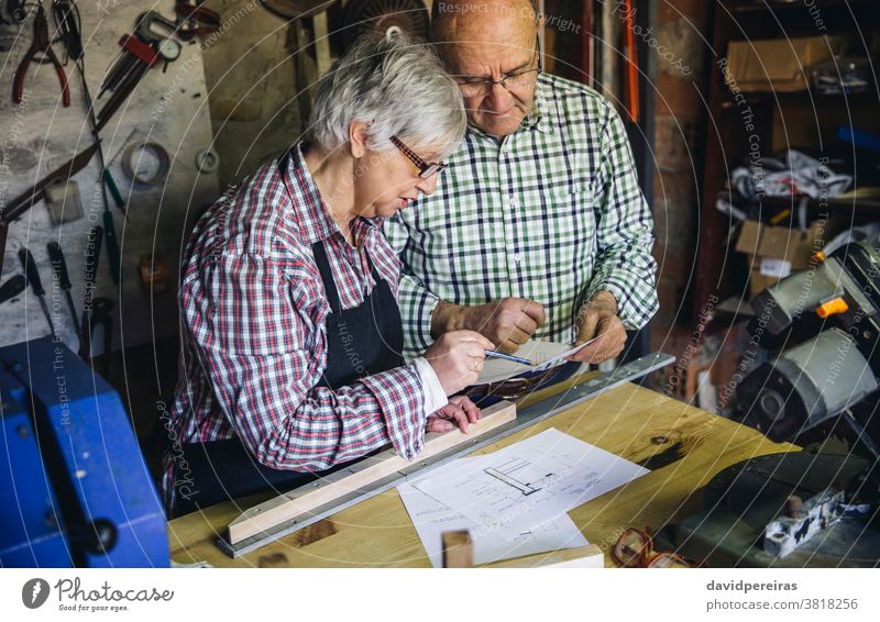 Seniorenpaar in einer Tischlerei Zimmerer Paar Schreinerei Blick plant arbeiten Zusammensein Werkstatt Holz reif Entwerfen Business Kaukasier heimwärts