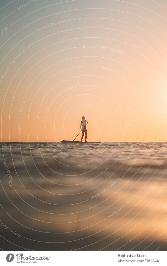 Frau rudert auf SUP-Brett im Meer Paddelbrett Sonnenuntergang MEER Holzplatte Surfbrett Reihe Aktivität Sommer Badeanzug Natur Wasser Feiertag