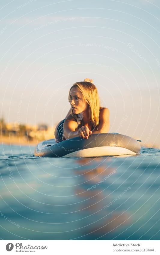 Gelassene Frau auf Surfbrett im Meer Lügen MEER sich[Akk] entspannen Sonnenuntergang schlank Badeanzug Wasser winken Himmel Erholung Sommer Badebekleidung ruhen