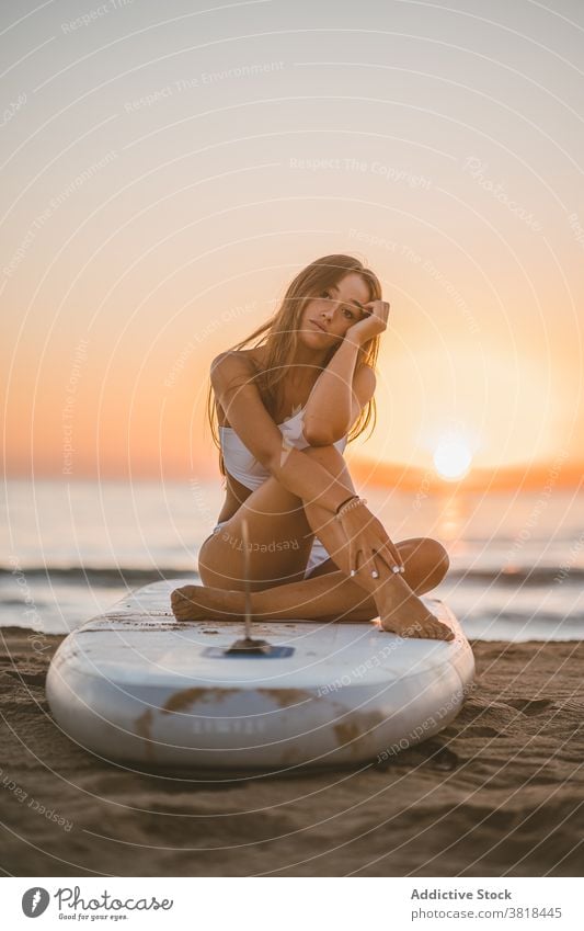 Sorglose Frau auf Paddleboard im Meer Paddelbrett sich[Akk] entspannen Sonnenuntergang SUP Holzplatte Sand Surfbrett schlank Badeanzug Sommer sitzen ruhen