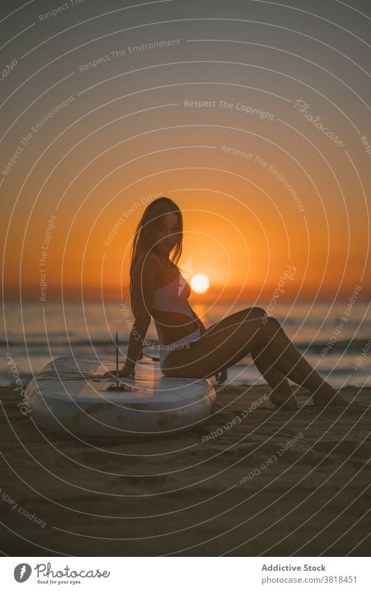 Schlanke Frau auf Paddle Board am Strand Paddelbrett SUP Holzplatte Sand Sonnenuntergang sitzen sich[Akk] entspannen MEER Badeanzug passen schlank Sommer Küste