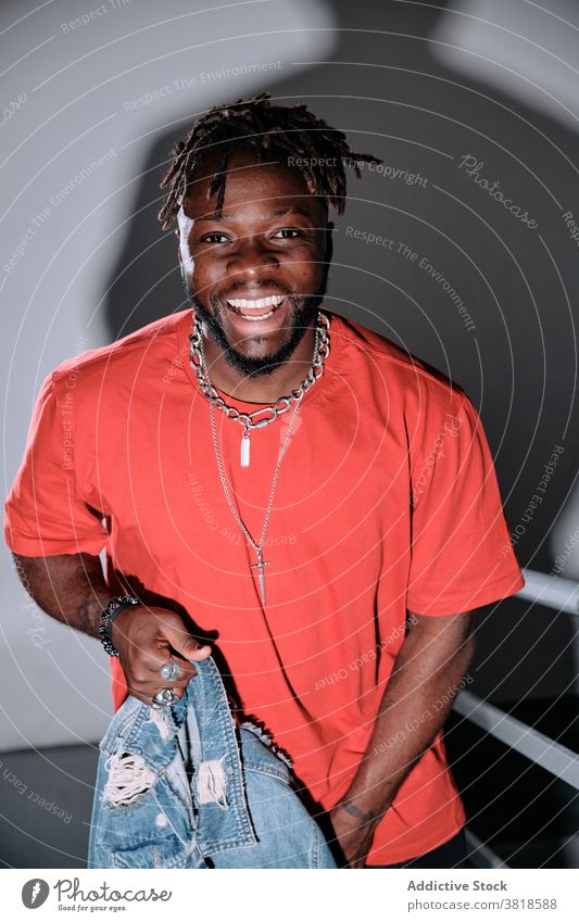 Lächelnder schwarzer Mann auf Metalltreppe Spaziergang nach oben Stil Outfit Treppe lässig Rastalocken Frisur männlich ethnisch Afroamerikaner trendy positiv