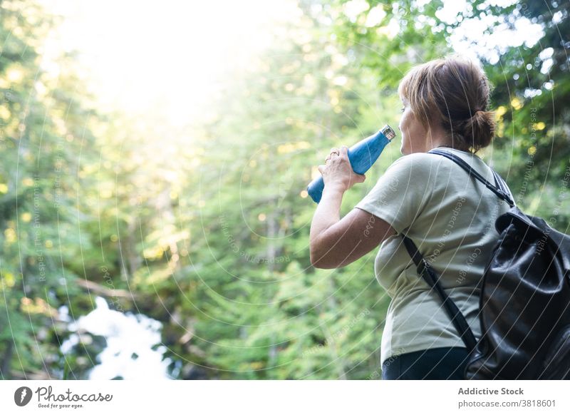 Weiblicher Tourist trinkt aus Wasserflasche in der Nähe von schnellen Fluss im Wald Reisender Frau Urlaub Bach Tal Berghang Uelhs deth Joeu Arantal lleida