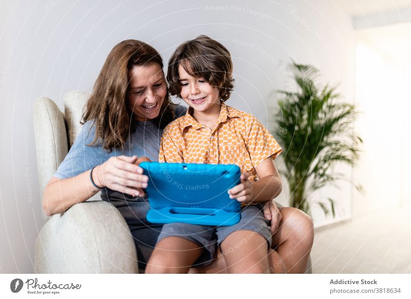 Aufgeregter Junge mit Laptop mit lächelnder Mutter zu Hause sitzen Liege aufgeregt Kindheit Browsen Mutterschaft freie Zeit Wochenende heimwärts benutzend
