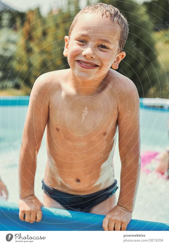 Glücklicher Junge steht in einem Pool authentisch Hinterhof Kindheit Kinder Familie Spaß Garten Fröhlichkeit Freude Lachen Lifestyle spielerisch Spielen