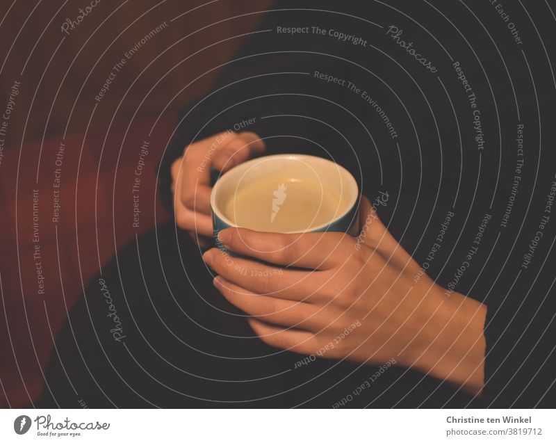 Gemütliche Kaffeepause. Eine Tasse mit Milchkaffee in den Händen einer jungen Frau. Kaffeetasse Kaffeetrinken genießen Duft Zufriedenheit gemütlich Pause ruhig