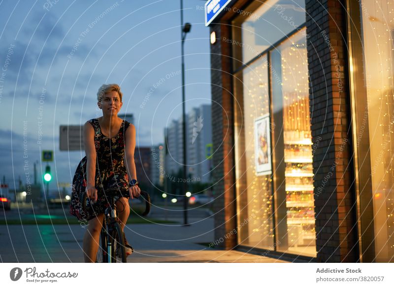 Frau im Kleid fährt Fahrrad in nächtlicher Stadt Abend Spaziergang Mädchen jung Reiten schön Großstadt Nacht Lichter Gebäude Glas Fenster Vitrine Laden