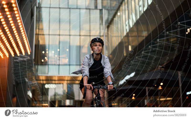 Weiblicher Kurier Radfahren in der Nähe von hohen Gebäude mit Glasfenstern in der Stadt Radfahrer gemauert Großstadt Tag Frau jung Sport Reiten Sommer