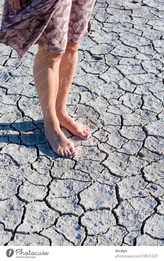 Frau steht barfuß auf ausgetrocknetem Boden, durch Trockenheit aufgerissene Erde Dürre Hitze Klimawandel Erderwärmung trocken Erdboden Trockenrisse heiß Beine