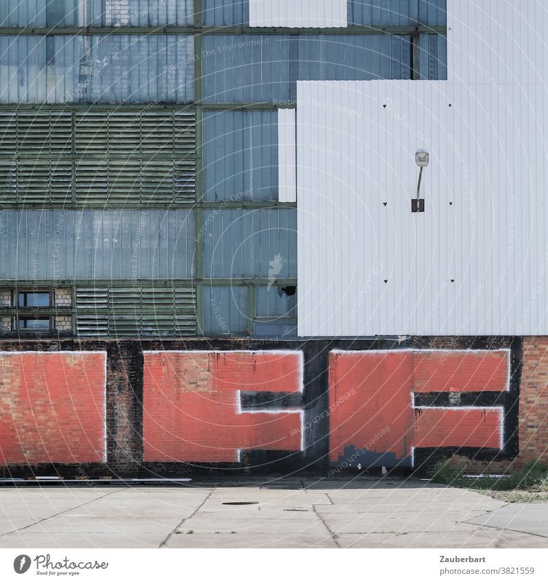 Wand einer Fabrik in weiß und grau mit rotem Graffiti frau Glas Jalousien Wellblech Stadt urban Verfall Mauer Industrieanlage Vergänglichkeit Fassade alt