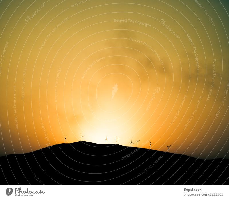 Windmühlen Turbinen Propeller Energie auf dem Hügel bei Sonnenuntergang mit einem orangefarbenen Himmel Hintergrund Wolken Landschaften Licht majestätisch