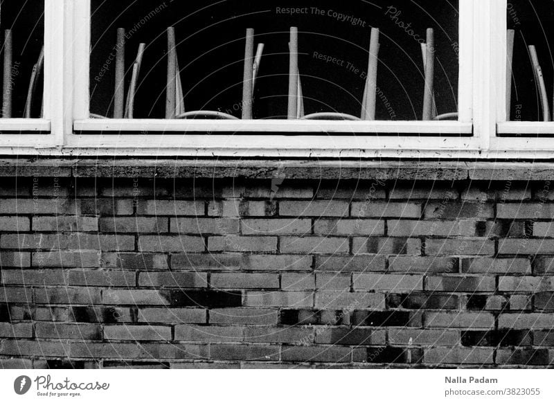 Hochgestellte Stühle Analogfoto analog Schwarzweißfoto Steine Wand Fenstersims Fensterrahmen Stuhlbeine verlassen Außenaufnahme Tag Fensterscheibe Fassade
