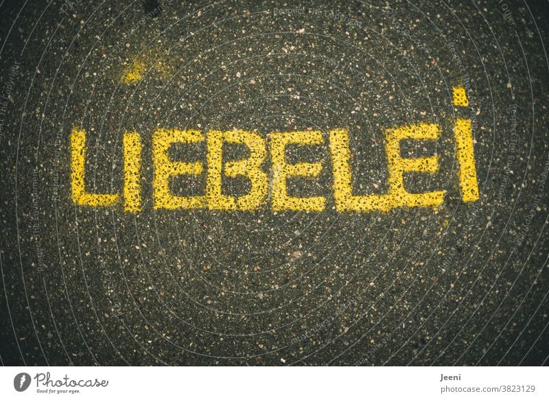 Ein Weg mit Straßenmalerei mit dem Wort "LIEBELEI" | Text auf einfarbigem neutralen Hintergrund Liebe Liebelei Asphalt Strassenmalerei malen Kreativität Kunst