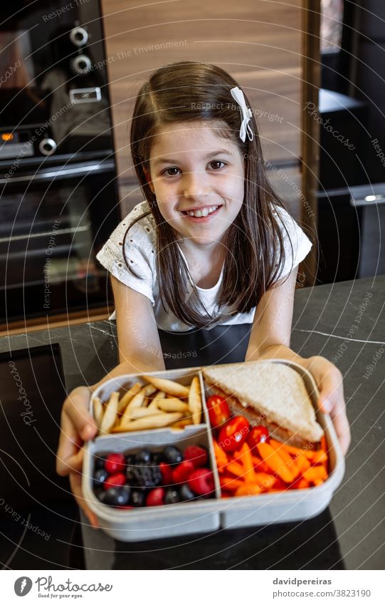 Glückliches Mädchen zeigt Lunchbox gefüllt mit gesundem Essen zeigend Schule Lunch-Box Gesundheit Lebensmittel Vegetarier gesunder Snack lecker Frucht Mitnahme