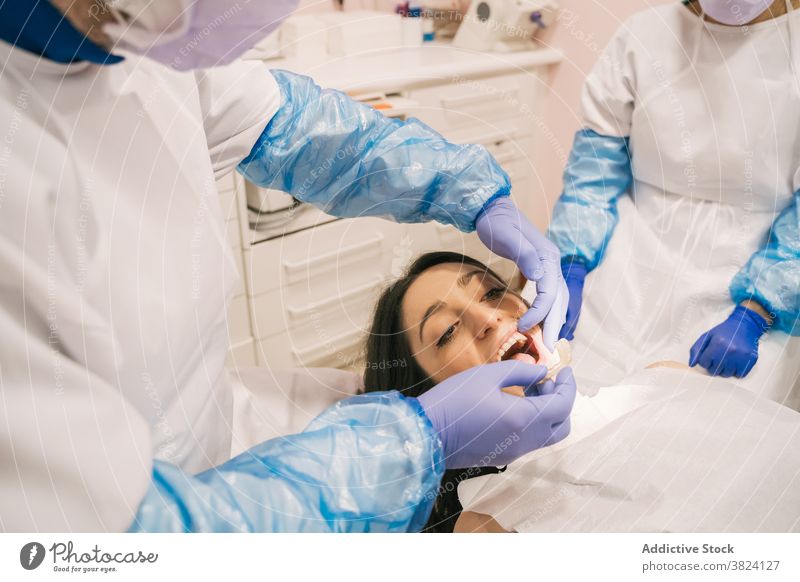 Anonymer Zahnarzt, der einem Patienten eine Zahnspange anlegt Kieferorthopäde angezogen Klammer geduldig mündlich kieferorthopädisch medizinisch