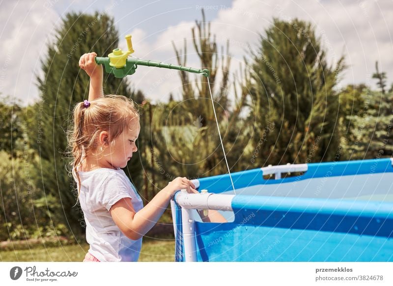 Kinder spielen mit Angelrutenspielzeug in einem Pool im Hausgarten authentisch Hinterhof Kindheit Familie Spaß Garten Fröhlichkeit Glück Freude Lachen Lifestyle