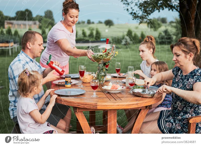 Familie isst während des Sommerpicknicks im Freien in einem Hausgarten zu Abend heimwärts Festessen habend Picknick Lebensmittel Mann Zusammensein Frau Kind