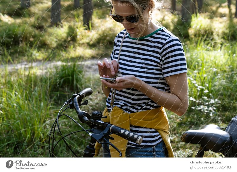 Frau mit Fahrrad sucht Weg auf Smartphone Fahrradfahren Navigation suchen Wald Fahrradtour Handy Freizeit & Hobby Tag Außenaufnahme Farbfoto Ausflug Natur