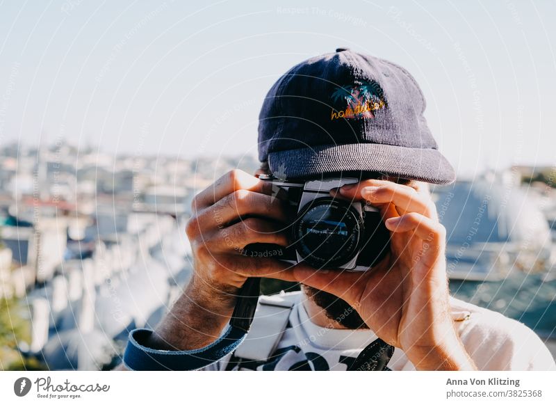 Analoges Fotografieren analog kappe Sonnenlicht Spiegelreflexkamera Hände Mann Stadt Städtereise Männerhände Hipster Fotokamera Sommer reisen Reisefotografie