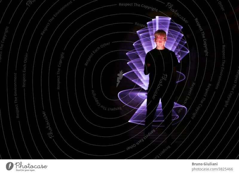 Silhouette eines Mannes, der ein Smartphone benutzt. Abstrakte Form bei der Lichtmalerei mit einem Lichtschwert. Vom Bildschirm beleuchtetes Gesicht.