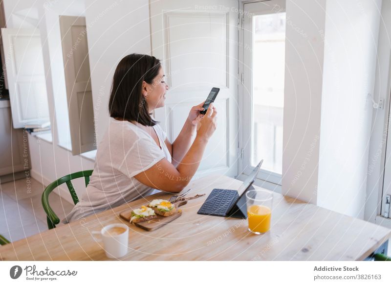 Frau beim Fotografieren während der Frühstückszeit im Innenbereich heimwärts Haus Mädchen Avocado kaufen Küche Kaffee Morgen Kaukasier brünett Tisch Lifestyle