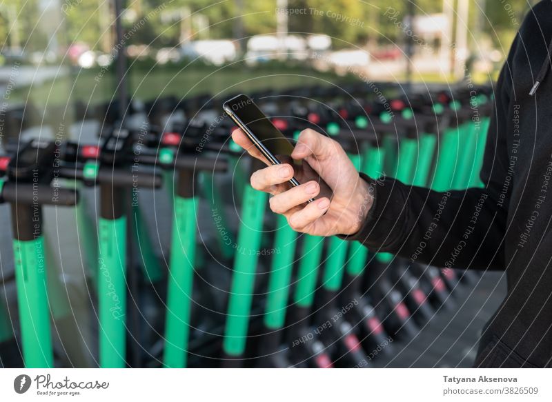 Mann benutzt mobile App zum Mieten eines Kickrollers elektrisch Tretroller Mobile Reiten Straße Großstadt Transport Lifestyle modern urban Person