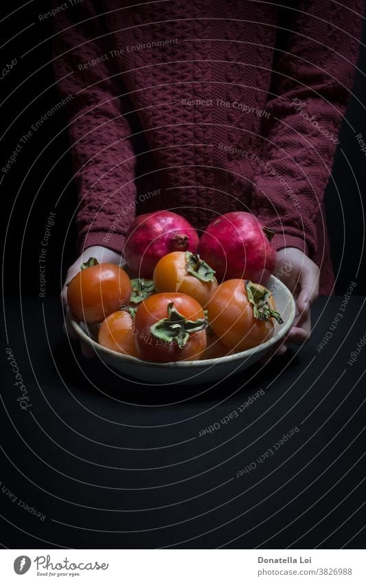 Teller Kakipflaume und Granatäpfel Herbst biologisches schwarzer Hintergrund Textfreiraum dunkel lecker Lebensmittel Früchte gut Hände Gesundheit Beteiligung