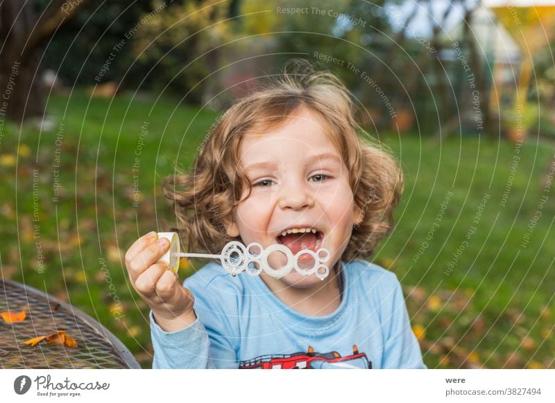Ein kleiner Junge macht Seifenblasen im Garten Blasen Kaukasier Kind Kindheit fliegend Fliegen. platzen zerbrechlich Spaß menschlich wenig Spielen s Seife
