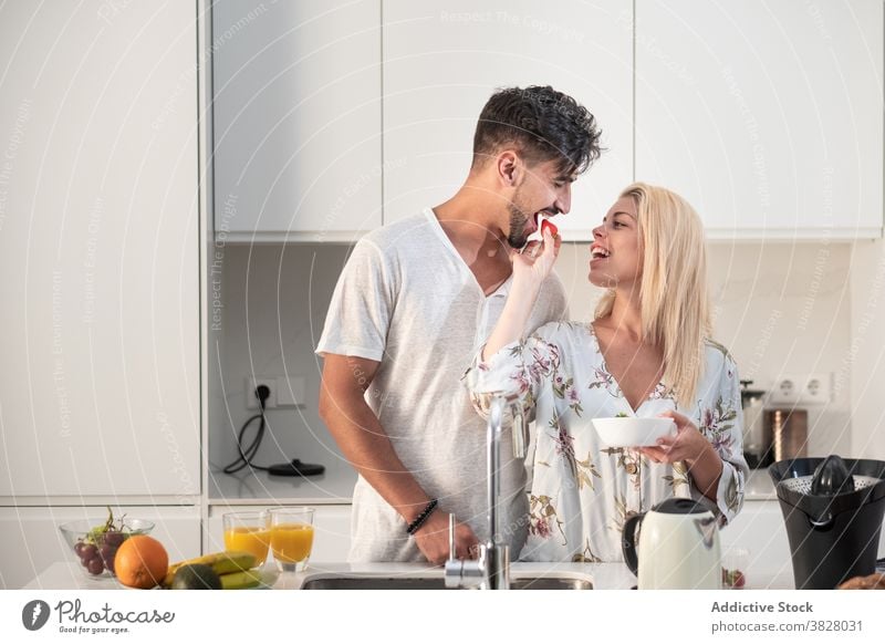 Verliebtes Paar beim Frühstück in moderner Küche Zusammensein Erdbeeren essen genießen Morgen Umarmung Liebe früh frisch orange Saft Lebensmittel Frucht