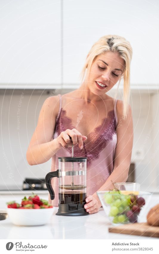 Frau bereitet Kaffee zum Frühstück vor französische Presse Kaffeemaschine heimwärts Küche früh Pyjama vorbereiten Abfertigungsschalter Seide Getränk trinken