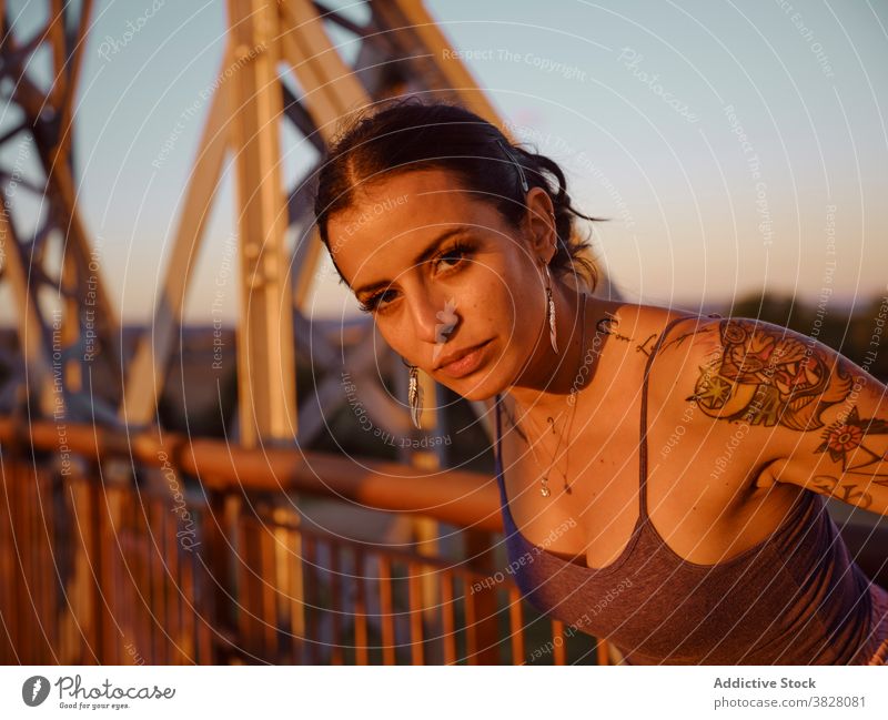Stilvolle Frau in Tattoos stehen in der Stadt trendy Brücke Metall Sonnenuntergang Sommer sich[Akk] entspannen ruhen genießen jung urban Freiheit Freude froh