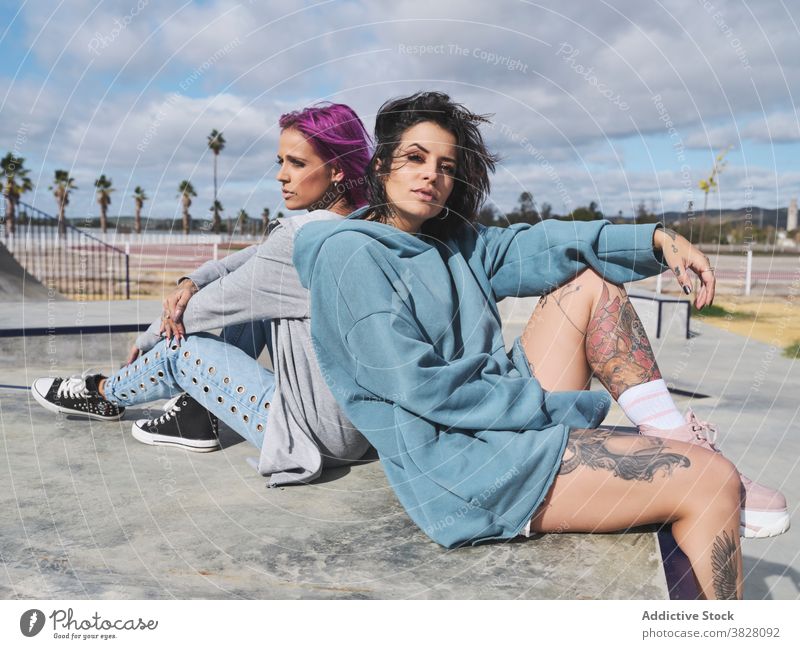 Stilvolle Frauen im Skatepark im Sommer rosa Haare informell Freund tausendjährig Hipster Zusammensein Tattoo Vorschein urban Straße exzentrisch Freundschaft