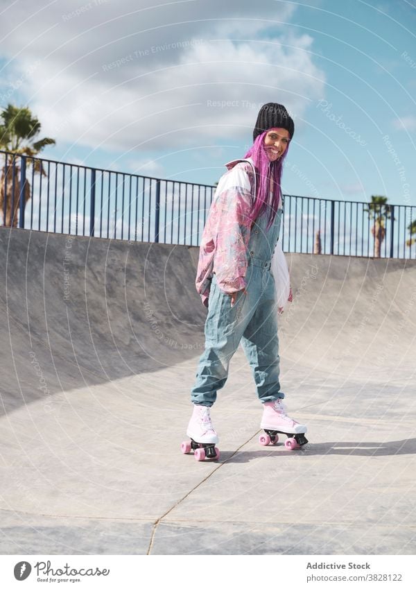 Stilvolle Frau mit rosa Haaren in Rollschuhen Rolle Skateplatz Schlittschuh Hipster Streetstyle informell exzentrisch Vorschein Hobby Spaß haben Outfit Straße