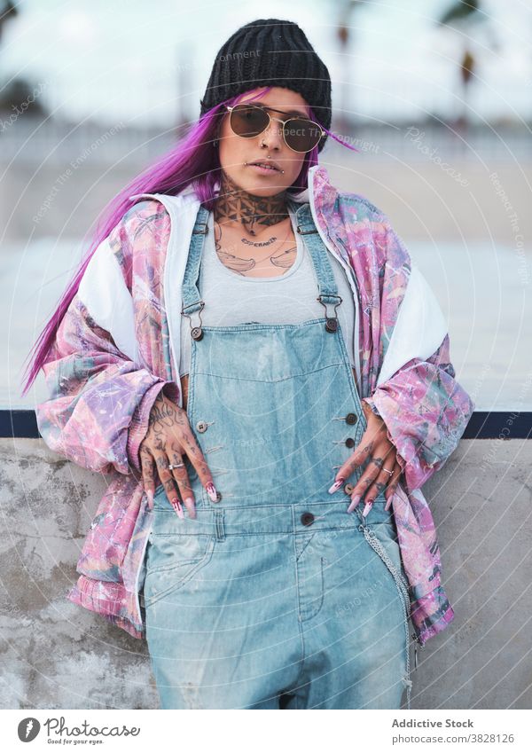 Frau im Hip-Hop-Outfit in der Stadt tausendjährig trendy ausgefallen Stil Sonnenbrille Tattoo Streetstyle Stilrichtung rosa Haare Großstadt cool jung urban