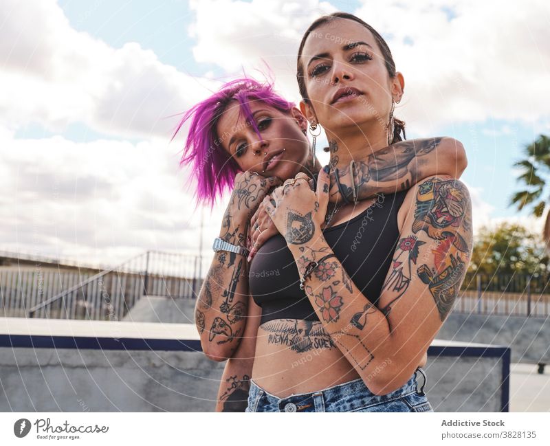 Informelle Frauen, die sich in der Stadt umarmen rosa Haare informell Freund tausendjährig Hipster Umarmung Zusammensein Tattoo Vorschein urban Straße