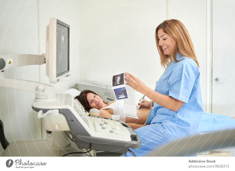 Arzt beim Betrachten von Ultraschallbildern in der Nähe des Scanners und unkenntlicher Patient Bild geduldig Sonographie Diagnostik Maschine prüfen Uniform