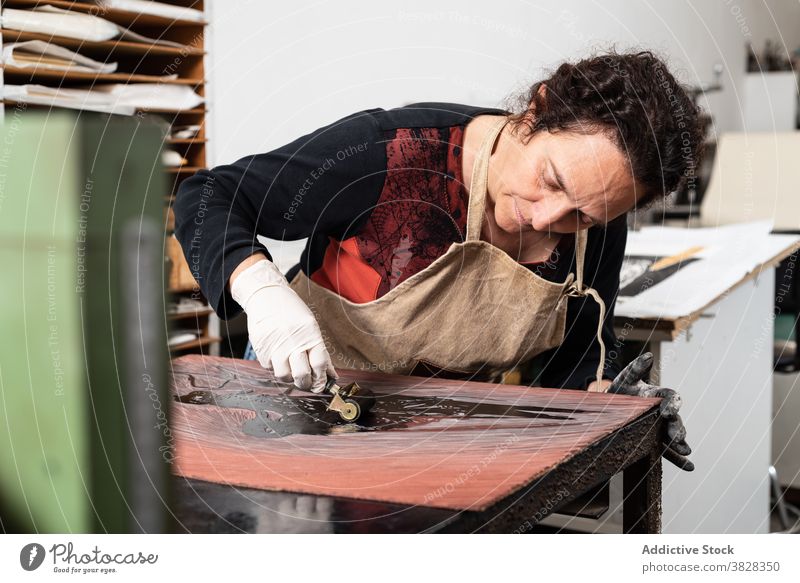 Handwerkerin bei der Herstellung eines Drucks in der Gravurwerkstatt gravieren Druckgrafik Tusche drucken kreieren Kunstgewerbler professionell Kunstwerk