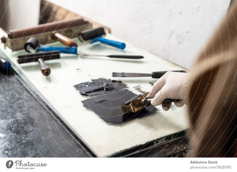 Kunsthandwerker mit Walze beim Auftragen von Farbe auf die Platte für die Gravur gravieren Druckgrafik Rolle Tusche drucken kreieren Handwerk Kunstgewerbler