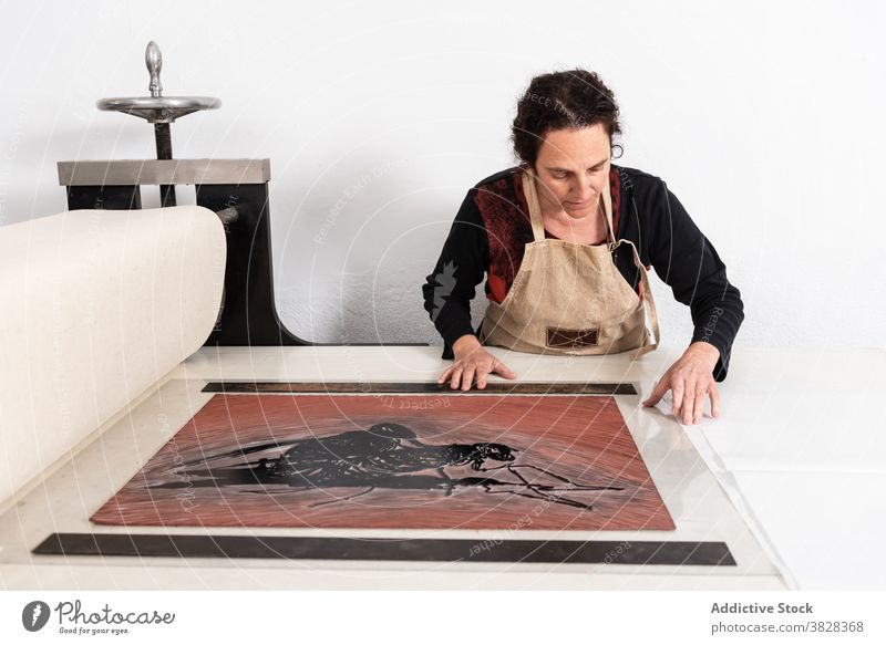 Druckerin ordnet Linolplatte mit eingefärbtem Muster in der Presse an Druckgrafik linocut drucken kreieren Handwerk Kunstgewerbler professionell Handwerkerin