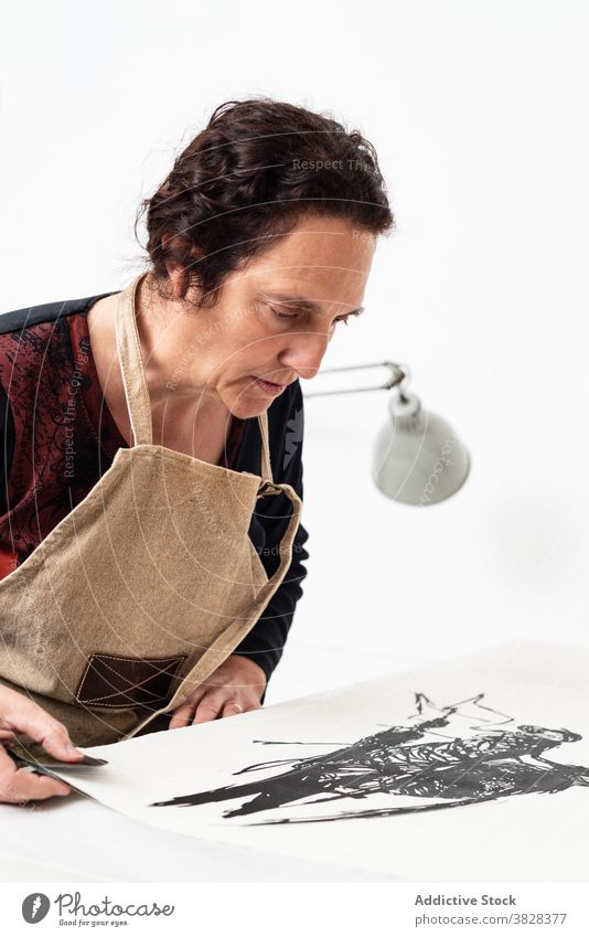 Künstler hält Papier mit Linolschnitt Druckgrafik drucken Eindruck kreieren Handwerk Kunstgewerbler professionell Kunstwerk Handwerkerin linocut Tusche Frau