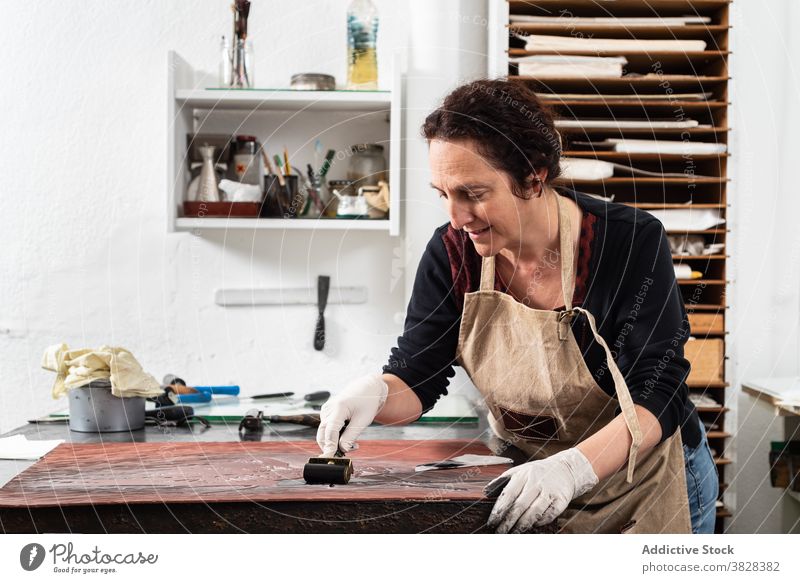 Handwerkerin bei der Herstellung eines Drucks in der Gravurwerkstatt gravieren Druckgrafik Tusche drucken kreieren Kunstgewerbler professionell Kunstwerk